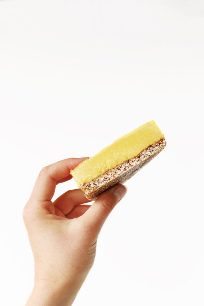 A hand holding a delicious golden slice of pumpkin spice flavoured vegan cheesecake.