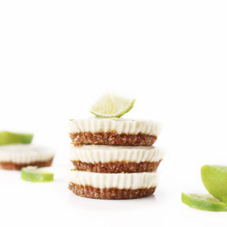 stack of dairy free gluten free mini vegan key lime pies with date and almond 'graham cracker' base topped with fresh green lime wedges