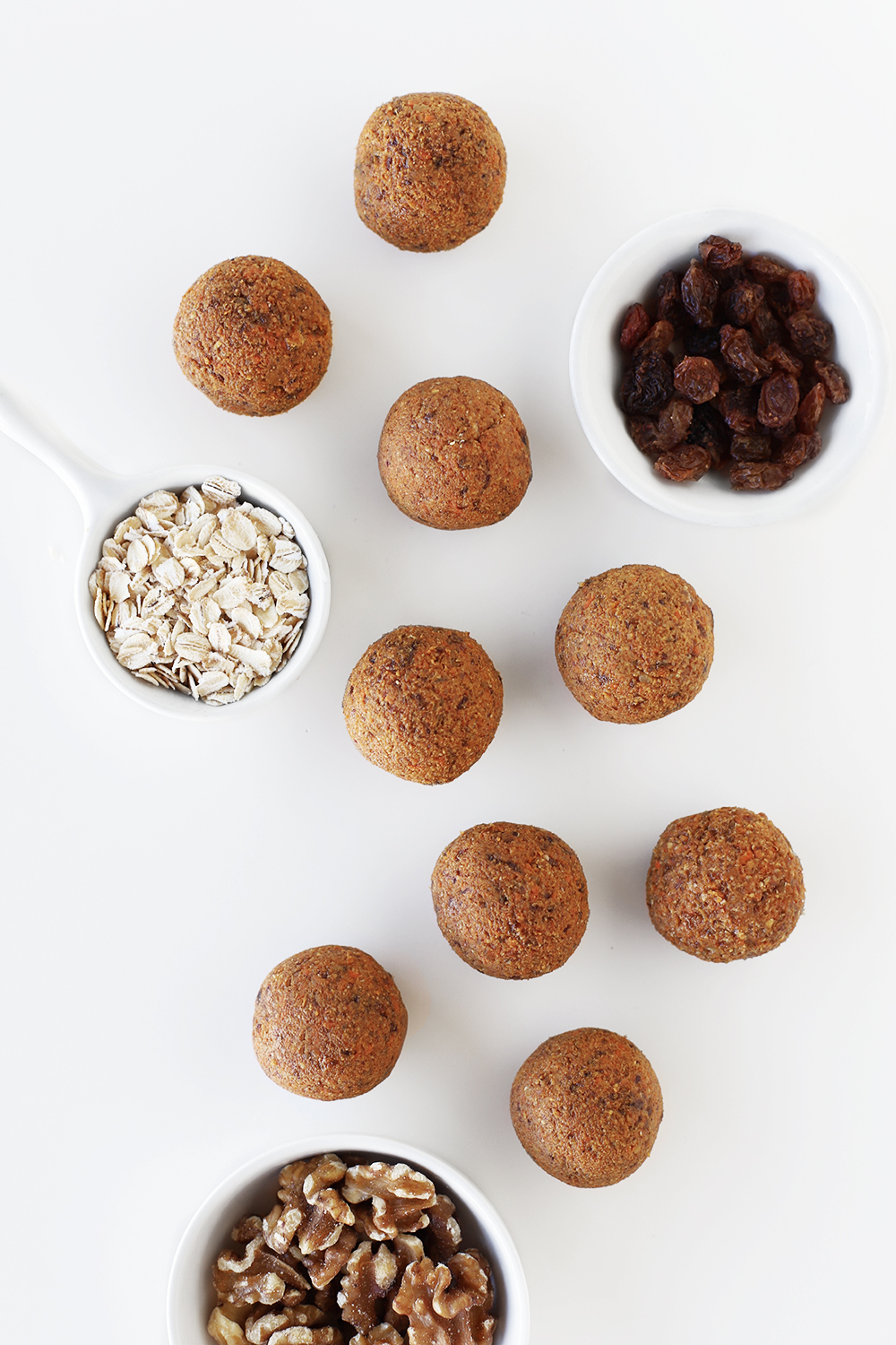 Carrot cake energy bite bliss balls and the healthy 5 ingredients they're made from in bowls: sulatnas/raisins, oatmeal, cinnamon, walnuts