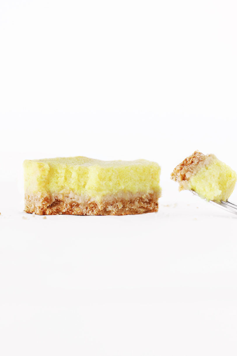 Cake fork taking a bite of a healthy vegan lemon bar with eggless lemon curd and buttery oatmeal crust