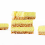 Stack of healthy vegan lemon bars with eggless creamy lemon curd on a buttery oatmeal crust and bite taken out of the top slice.