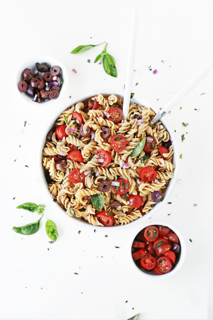 vegan italian pasta salad with red lentil protein pasta spirals, cherry tomatoes, kalamata olives, fresh, basil, red onion and zesty italian vinegar salad dressing