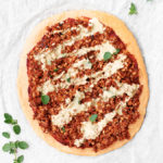 high protein vegan rede lentil pizza base gluten free with Italian suasage crumbles, herbs tomato paste and tahini cheese sauce,