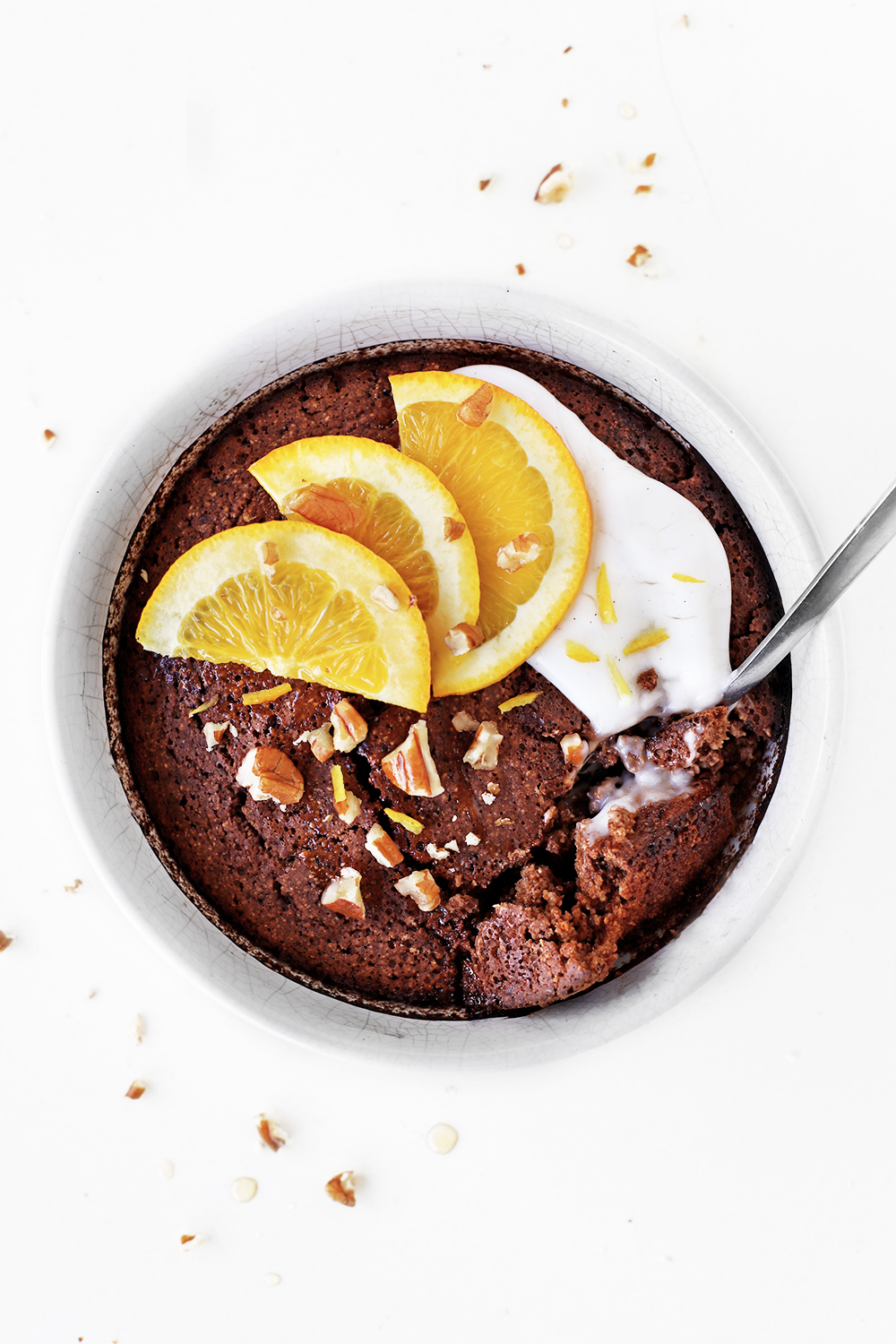 Ceramic bowl of Chocolate Orange Baked Oats topped with dairy free coconut yoghurt, orange segments and chopped nuts